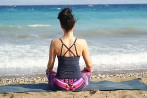 Lady sitting on beach in yoga clothes