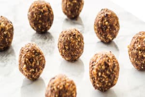 Energy protein balls with healthy ingredients on marble table. Home made with dates, peanut butter, flax and chia seeds, oats, almond and chocolate drops.