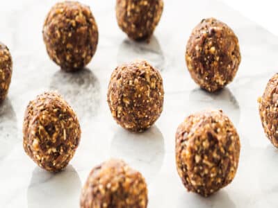 Energy protein balls with healthy ingredients on marble table. Home made with dates, peanut butter, flax and chia seeds, oats, almond and chocolate drops.