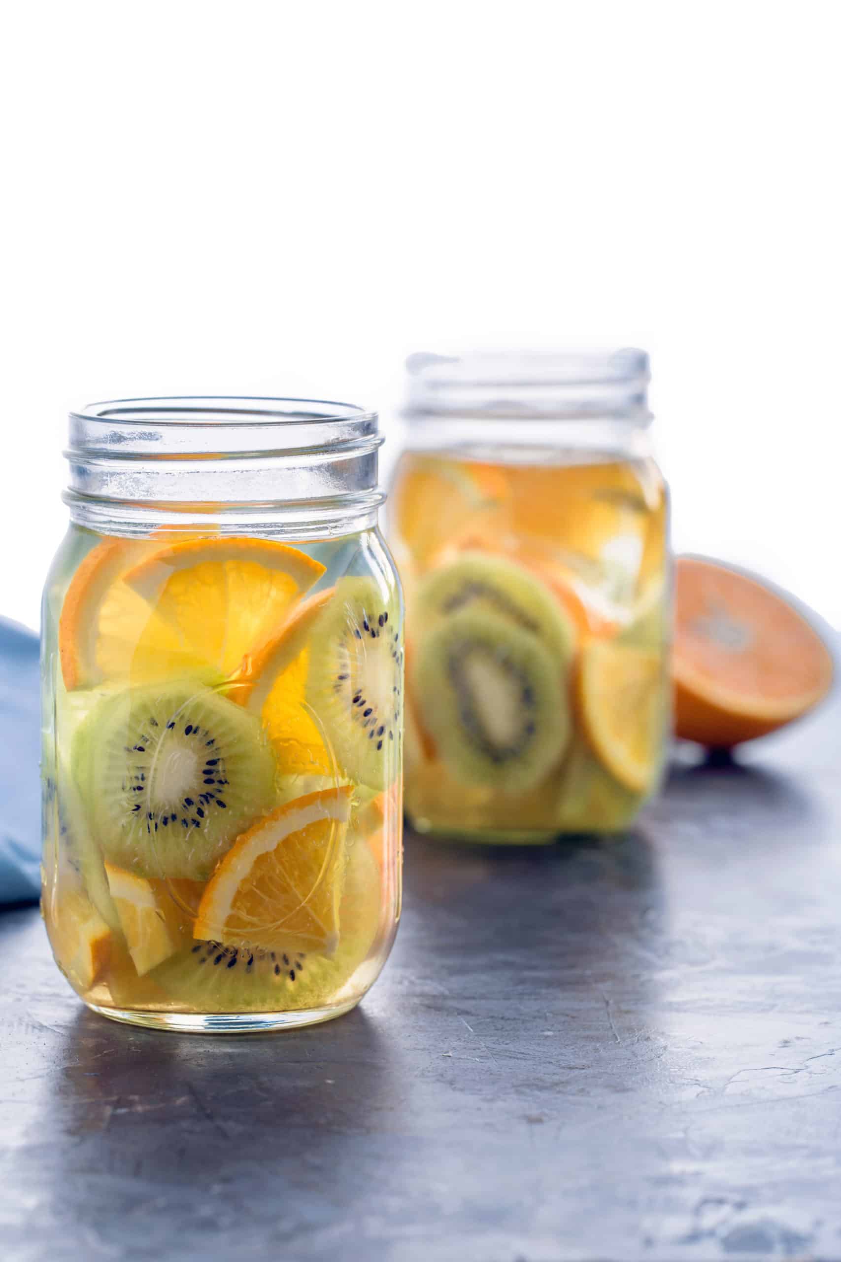 2 mason jars with slices of orange and kiwi