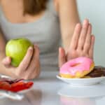 Woman choosing apple over donuts