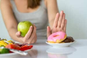 Woman choosing apple over donuts