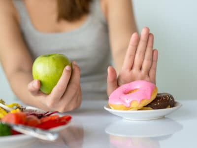 Woman choosing apple over donuts