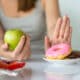 Woman choosing apple over donuts