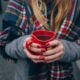 A girl wearing a scarf and holding a cup of tea