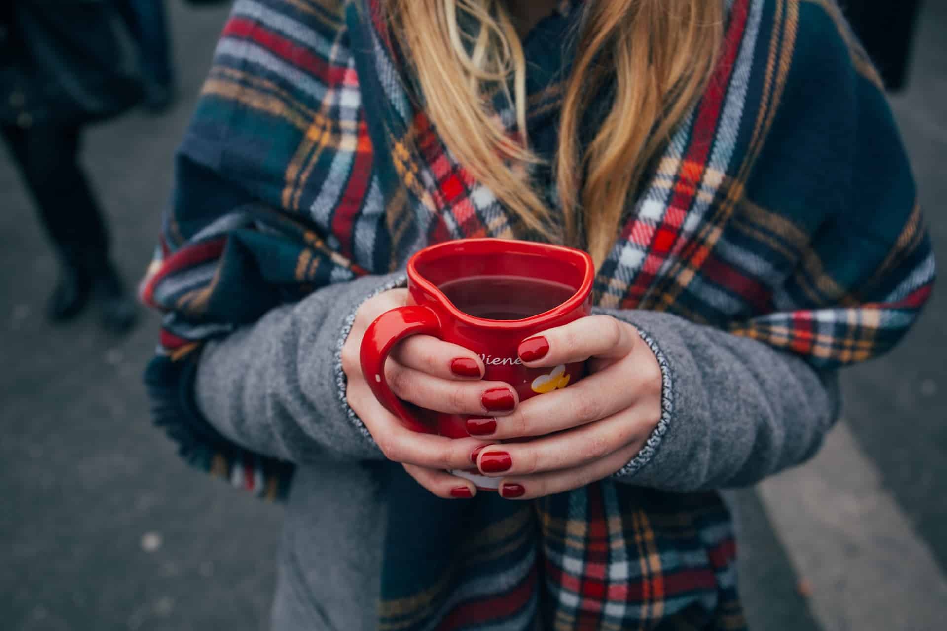 A girl wearing a scarf and holding a cup of tea