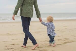 Woman walking towards the ocean with her son