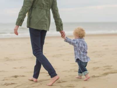 Woman walking towards the ocean with her son