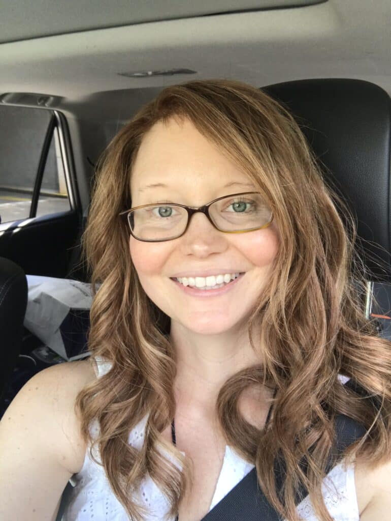 Woman wearing a wig smiling in a car selfie during cancer treatment