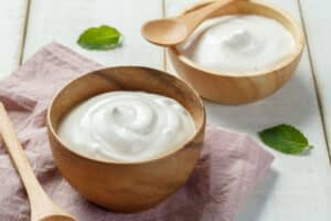 Homemade yogurt in a wooden bowl with a wooden spoon and napkin.