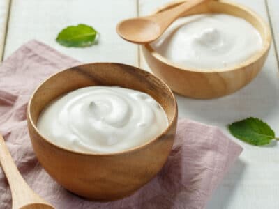 Homemade yogurt in a wooden bowl with a wooden spoon and napkin.