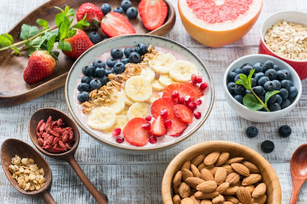 An array of healthy and colorful breakfast foods including berries, bananas and oats in a forager bowl